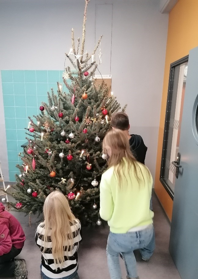 Schüler schmücken einen Weihnachtsbaum 